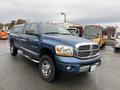 A blue 2006 Dodge Ram 2500 pickup truck with a silver grille and chrome bumpers parked with orange lights on the roof
