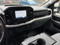 Interior view of a 2021 Ford F-150 featuring a central touchscreen display dashboard controls and seating area with cup holders