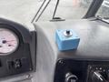A blue button panel with a round black button sits on a textured dashboard next to a fuel gauge and various controls in a fire truck cab