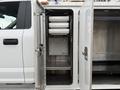 A 2018 Ford F-550 with open storage compartments featuring multiple drawers and a small appliance inside
