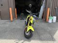 A bright yellow 2018 Honda Grom motorcycle with a small frame and distinctive headlight design facing forward