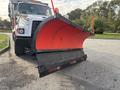 A 2013 Freightliner 114SD snow plow with a black and orange blade positioned at an angle ready for snow removal