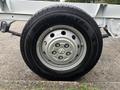 A close-up of a black tire mounted on a silver rim with six lug nuts designed for a 2023 RAM Promaster 3500