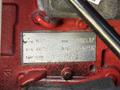 A metal identification plate with various numbers and codes attached to a red surface