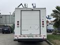 A 2012 Ford E-450 Super Duty van with a white exterior and a large roll-up door at the rear