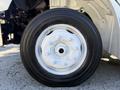 A close-up of a white wheel and tire of a 2017 Freightliner M2 106 showcasing the wheel's five lug nuts and thick black rubber tread