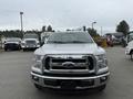 A white 2015 Ford F-150 pickup truck is facing the camera with a chrome grille and headlights clearly visible