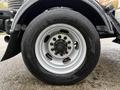 Close-up of a silver alloy wheel and tire mounted on a 2024 RAM 5500 showing multiple black lug nuts on the wheel hub