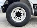 Close-up of a black tire with white rim and multiple lug nut holes shown on a 1998 Freightliner FL80