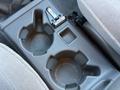 Cup holder console area in a 2004 Toyota Tacoma featuring two cup holders and a small storage compartment