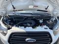The image shows the engine compartment of a 2019 Ford Transit 350 with various components including the air intake hose and different fluid reservoirs