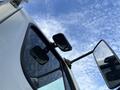 A close-up view of the side mirrors and windshield of a 2013 Freightliner 114SD truck with a clear sky in the background