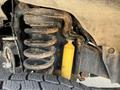 A close-up view of the suspension system of a 2014 Ford F-250 SD showing a coil spring and a yellow shock absorber with some visible rust