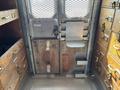 Interior view of a 2008 Workhorse W62 showing metal and wood cabinetry with drawers a metal chair mounted on the wall and a double door featuring a mesh grate