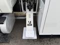 A white hydraulic leg of a 2011 International 4300 truck with warning labels and a flat base mounted on the ground