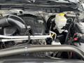 Engine compartment of a 2015 RAM 2500 showing the engine block various hoses and components including the battery and coolant reservoir