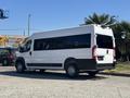 A white 2020 RAM ProMaster 3500 van with large windows and a black lower section parked in an outdoor area