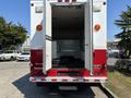 A 2007 GMC C4500 TopKick ambulance with open rear doors revealing an empty interior and black seating area