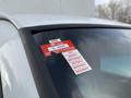 A 2015 GMC Savana with a certification sticker affixed to the windshield displaying an approval number and months of July to December