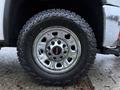 Close-up of a chrome wheel hub and off-road tire of a 2017 GMC Sierra 3500HD showcasing the rugged tread design and distinctive GMC emblem on the wheel