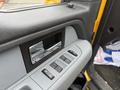 A close-up of the interior door panel of a 2014 Ford F-150 featuring window control buttons and a metallic door handle