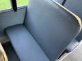 A seat in a 2014 International 4300 bus with a smooth dark vinyl surface and a simple design featuring a wide seating area