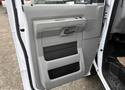 The interior door panel of a 2019 Ford Econoline featuring a gray plastic finish and a built-in armrest with storage compartments