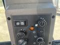 Control panel of a 2011 Case 570 MXT featuring switches and dials for various functions and an orange indicator light