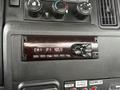 Close-up of a car stereo display panel featuring a digital screen showing radio station information and various control buttons for tuning and volume adjustment