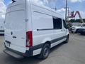 A white 2022 Mercedes-Benz Sprinter van with a sliding door and black trim parked at a work site