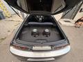 A 1997 Toyota Supra with an open trunk revealing two large subwoofers installed in the cargo area