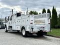 A 2005 Freightliner M2 106 service truck with a white body featuring multiple storage compartments and equipment mounts on the sides and back