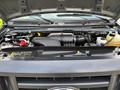The engine compartment of a 2013 Ford E-350 Super Duty with visible components including the air intake the battery and various fluid reservoirs
