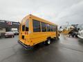 A yellow 2021 Ford Econoline school bus viewed from the rear showing its large windows and distinctive design
