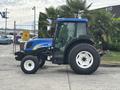 A blue and black 2009 New Holland T4020 tractor with large tires and a cab featuring a front windshield and open door facing left