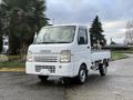 A white 2009 Suzuki Carry small truck parked with a simple cab design and an open cargo bed