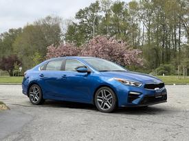 A blue 2021 Kia Forte with a sleek design featuring a distinctive front grille and sporty wheels parked at an angle.