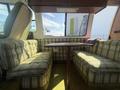 A 1976 GMC Motorhome interior featuring plaid seating and a central table with a wooden finish