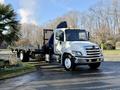 A white 2015 Hino 358 truck with a flatbed and hydraulic crane positioned in a parking area