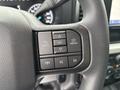Close-up of the steering wheel controls in a 2023 Ford F-450 Super Duty featuring buttons for navigation and media functions