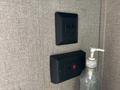 A black electrical outlet with two switches and a red safety button alongside a clear soap dispenser