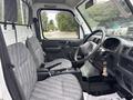 Interior of a 2010 Suzuki Carry featuring two front seats with gray fabric upholstery and a simple dashboard with steering wheel and gear stick