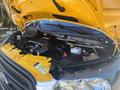 Close-up of the engine compartment of a 2017 Ford Transit-350 with a yellow hood open showing various engine components and fluids