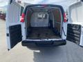 A 2022 GMC Savana cargo van with its rear doors open displaying a spacious, empty interior with a wooden floor and a metal divider wall