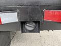 A fuel tank fill opening on the rear of a 2020 Ford F-550 with a black cover and reflective tail lights on either side