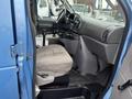 Interior of a 2006 Ford Econoline showing the driver's seat steering wheel and dashboard with cup holders and control panels