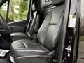 A 2022 Mercedes-Benz Sprinter interior featuring two black leather front seats with armrests and a steering wheel in close proximity