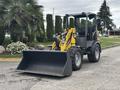 A 2014 Wacker Neuson WL34 compact wheel loader with a large front bucket and yellow accents parked on a roadway