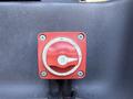 A red battery disconnect switch with an on and off marker positioned on a black panel in a Chevrolet Express