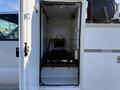 A white 2009 Ford F-550 with an open service compartment revealing empty racks and mechanical equipment inside